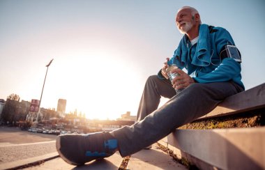 Şehirdeki antrenmandan sonra kıdemli adam dinleniyor. Fitness, spor ve sağlıklı yaşam tarzı kavramı.