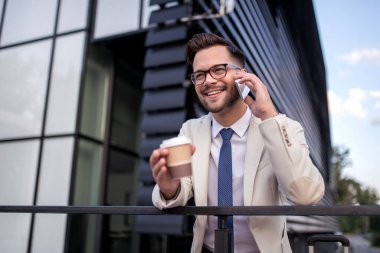 Genç iş adamının portresi, telefon edip kahve içerek gidiyor..