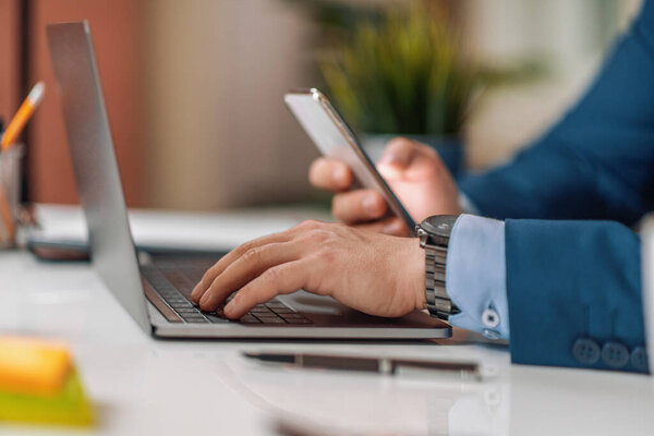 Закрывай. Мужчина бизнесмен работает с телефоном и ноутбуком в офисе.