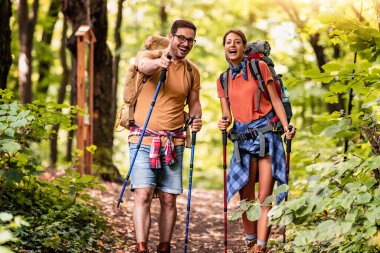 Aktif genç çift ormanda sırt çantalarıyla yürüyüş yapıyor, yeni maceranın tadını çıkarıyor..