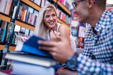 Kütüphanede kitap arayan genç bir öğrenci. İnsanlar, eğitim, öğrenme ve yaşam tarzı kavramı.