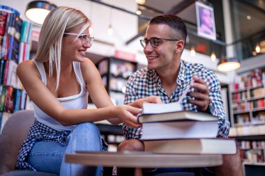 Kütüphanede kitap arayan genç bir öğrenci. İnsanlar, eğitim, öğrenme ve yaşam tarzı kavramı.