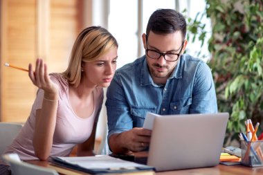 Stressed married couple at home use laptop and paying bills online.