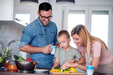 Family making salad in kitchen at home,cutting vegetables and preparing for lunch.
