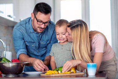 Family making salad in kitchen at home,cutting vegetables and preparing for lunch.