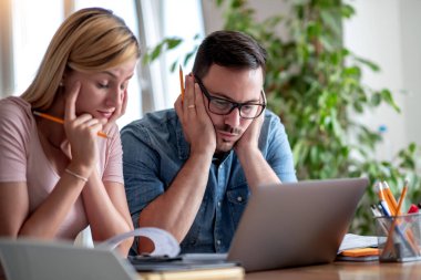 Stressed married couple at home use laptop and paying bills online.