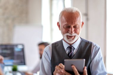 Senior businessman using tablet in their office.