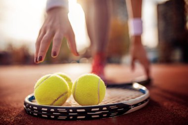 Young female tennis player with tennis ball and racket on court.