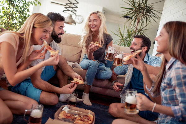 Friends enjoying together, eating  pizza and drink beers at home.