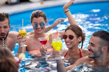 Bir grup arkadaş havuzda parti veriyor, kokteyl içiyor ve birlikte eğleniyorlar..