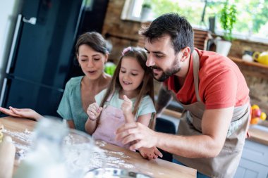 Mutlu Kafkasyalı baba, anne ve kız mutfakta hamur işleriyle uğraşırken.