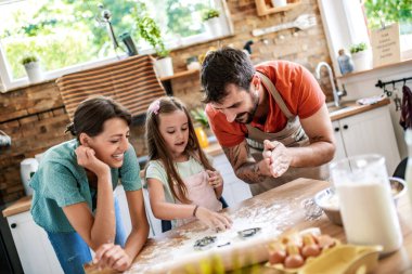 Mutlu Kafkasyalı baba, anne ve kız mutfakta hamur işleriyle uğraşırken.