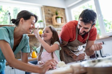 Mutlu Kafkasyalı baba, anne ve kız mutfakta hamur işleriyle uğraşırken.