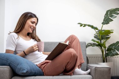 Evde kitap okuyan güzel bir kadın. Halk, eğitim ve yaşam tarzı kavramı.