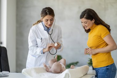 Anne ve şirin bebeği klinikte çocuk doktorunu ziyaret ediyor. Bebek doktoru ve doktor ofisinde bebeği var..
