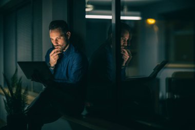 Ekonomik sorunlar ve iş için zor zamanlar. Düşünceli ve endişeli ifadesiyle dizüstü bilgisayarı izleyen bir iş adamı. Yoğun çalışma günü.