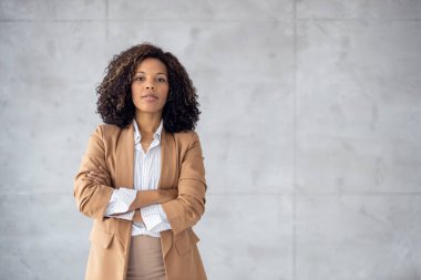 İşteki gülümseyen iş kadını. Gri arka planda poz veren güzel Afro-Amerikan iş kadını. Kameraya bakıyorum..