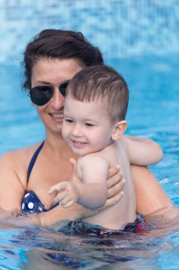 Genç anne ve oğlu eğlenceli bir yüzme havuzuna sahip