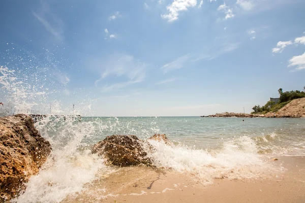 Splashes of sea wave on the beach, blue sky — Stock Photo, Image