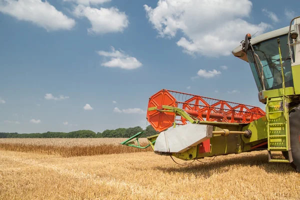 Combiner moissonneuse sur un champ de blé avec un ciel nuageux — Photo