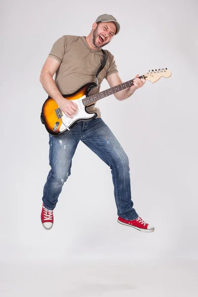 Homem jogar na guitarra elétrica e pulando no ar — Fotografia de Stock