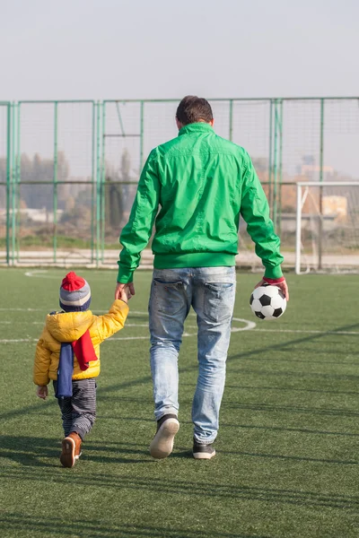 Padre joven con su hijo pequeño van a jugar fútbol, fútbol en el parque —  Fotos de Stock