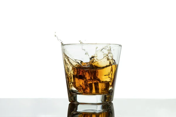 アイススプラッシュ付きのウィスキーグラス 白に隔離された氷でウイスキーを振りかけるガラス — ストック写真