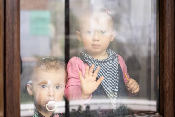 Pencereden Dışarı Bakan Iki Üzgün Kız Ikiz Bebek Evde Kalıp — Stok fotoğraf