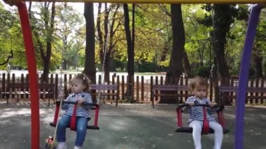 İki küçük kız, oyun alanında oynuyorlar. Çift yumurta ikizi kardeşler, salıncakta sallanıyorlar