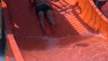 Baba ve oğul yaz tatilinde su parkında kayıyor. Tatilde mutlu bir aile. Yavaş çekim 240 fps
