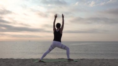 Kumsalda yoga yapan bir kadın. Açık hava sporları. Sağlıklı yaşam.