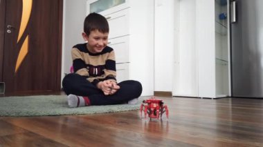 Çocuk evde yerde örümcek robot oyuncağıyla oynuyor.