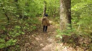 Küçük çocuk ormanda yürüyor. Küçük kaşif