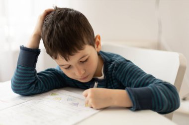 Evde ödevleriyle boğuşan genç bir çocuğun portresi. Çocukların evde eğitim konsepti. Uzaklık öğrenimi