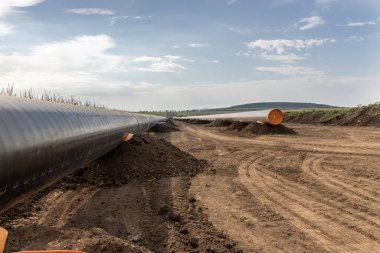 Gaz ve petrol boru hattı inşaatı. Borular kaynaşmış. Büyük boru hattı yapım aşamasında. Bulutlu gökyüzü