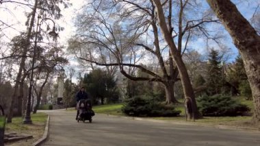 Parkta iki çocuklu bir baba. İkiz bebek arabasını iten adam..