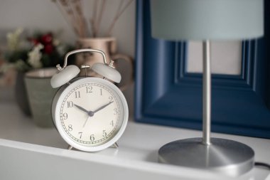 Yatak odasındaki yatak odasındaki beyaz çalar saat..