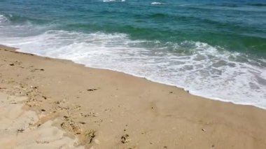 Kumsal, köpüklü okyanus, kumları yıkayan deniz dalgaları. Dalgalar kumsala vuruyor. Dalgaların sesi