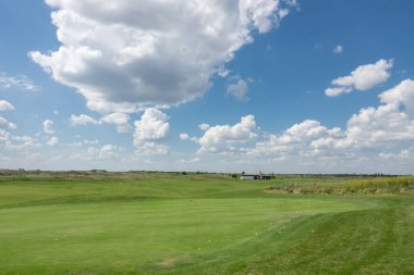 Golf sahasında bir sürü sarı top var. Oyuncular ısınıyor