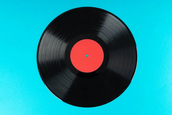 Old vinyl disc on blue background. Old vintage vinyl record.