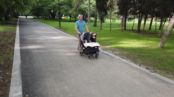 Far Med Børn Dobbelt Klapvogn Park Mand Skubber Tvillinger Klapvogn – Stock-video