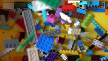 Renkli plastik oyuncak tuğlaları kutuya düşüyor. Yavaş çekim 240 fps, yukarıdan aşağıya görünüm