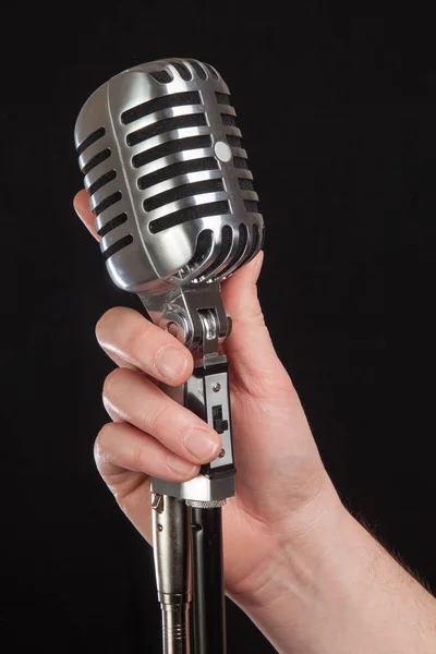 Hand som håller en retro mikrofon över svart bakgrund — Stockfoto