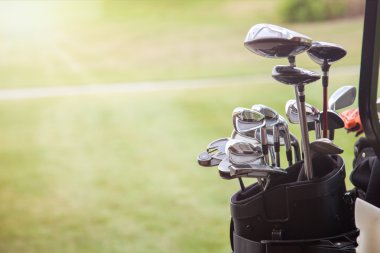 set of golf clubs over green field background clipart