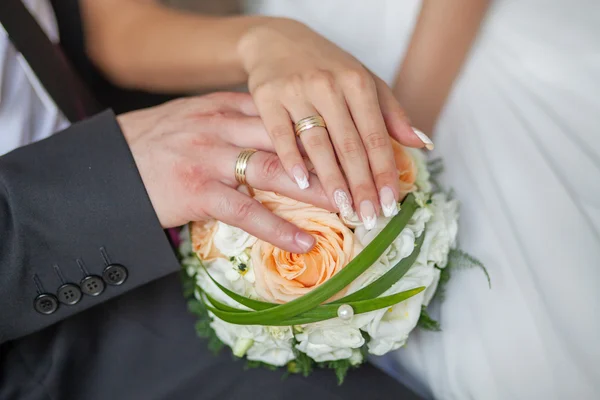 Bruid en bruidegom handen met trouwringen en bloemen boeket — Stockfoto