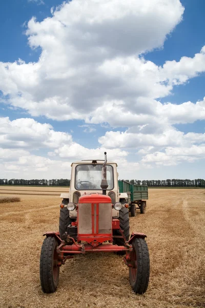 Old tractor in field, against a cloudy sky — Stock Photo, Image