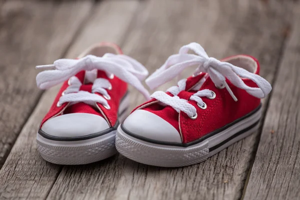 Rote Baby-Turnschuhe auf Holzgrund — Stockfoto