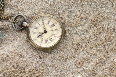 Old pocket watch in the sand clipart