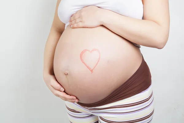 Barriga de mulher grávida com coração desenhado — Fotografia de Stock