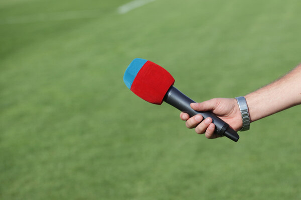 hand holding microphone for interview during a football mach